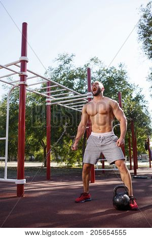 Sporty and healthy muscular man exercising outdoors. Sexy young man with a muscular body on a natural background. Strong and perfect male body.