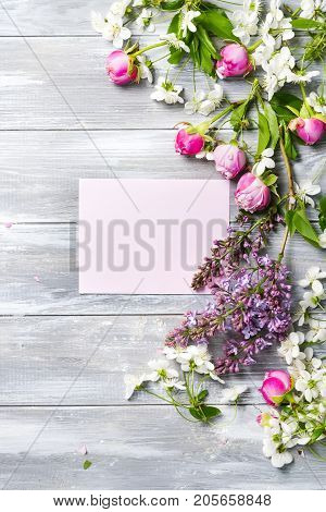 white greeting card decorated with a pattern of flowers and leaves on a gray wooden background flat lay