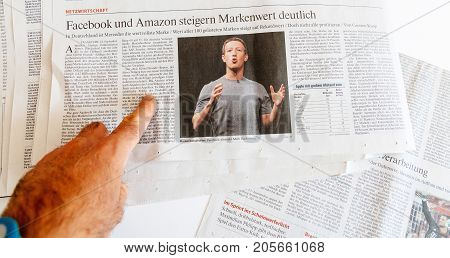 PARIS FRANCE - SEP 25 2017: Man reading international newspaper about Mark Zuckerberg Facebook CEO intention to sell 18% of social network stocks