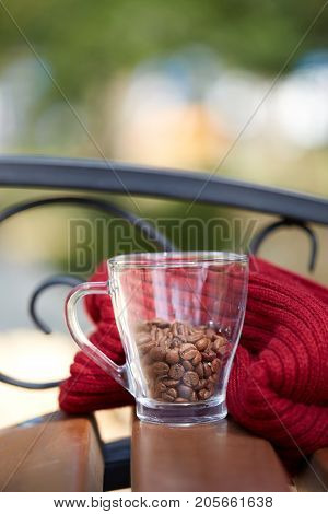 Cup of coffee beans on the table with red scarf. Close-up. Copy space.
