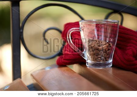 Cup of coffee beans on the table with red scarf. Close-up. Copy space.