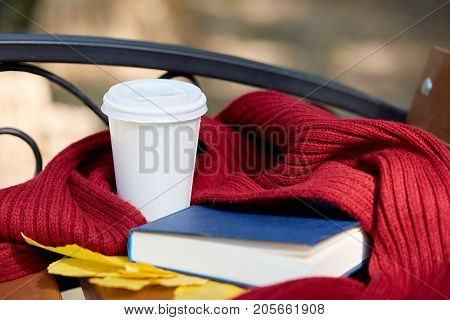 A glass of teaa is on a brown table with a warm scarf and an interesting book Close-up of equipment.