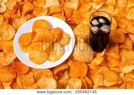Golden Chips Potato Texture. Chips On A White Plate Standing On A Large Pile Of Chips With Glass Of