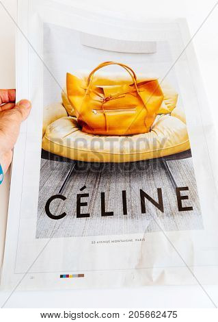 PARIS FRANCE - SEP 25 2017: Man reading international newspaper looking at Celine bag fashion advertising on the last page of French newspaper