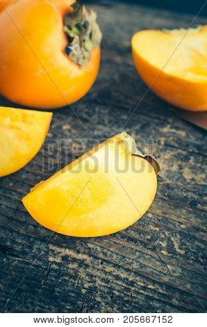 Slice of ripe delicious fresh persimmon kaki fruit on old wooden table.