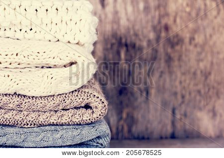 A stack of woolen sweater plaid. Warm clothing. Home atmosphere winter clothing. Gray white and brown sweater. Warm and cozy. Knitted clothes. Cozy atmosphere.