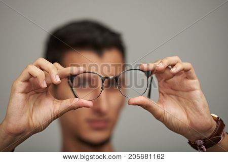 Glasses on man hands close up in blurred background