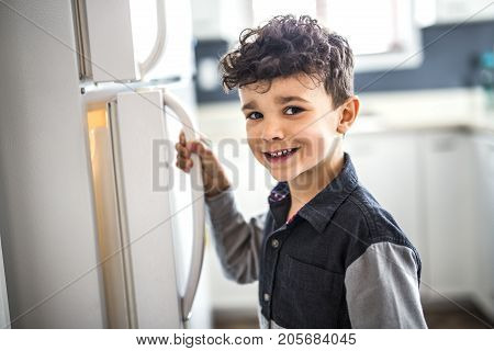 A Young white boy standing in front of open refrigerator.