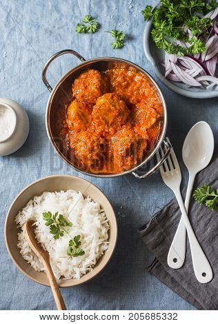 Chicken curry sauce meatballs and rice on a blue background top view. Indian food. Healthy food concept
