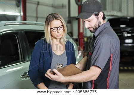 An auto mechanic and female customer in garage