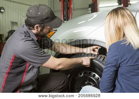 An auto mechanic and female customer in garage