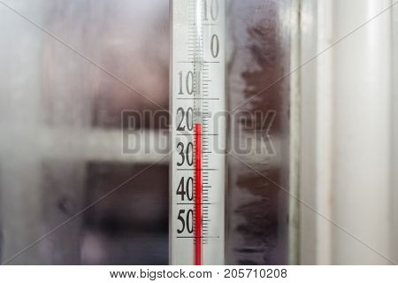 Close-up view through frozen window from house to the outdoor thermometer which showing subzero temperature.