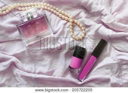Women's perfume pearl beads and cosmetics on pink fabric. Toning.