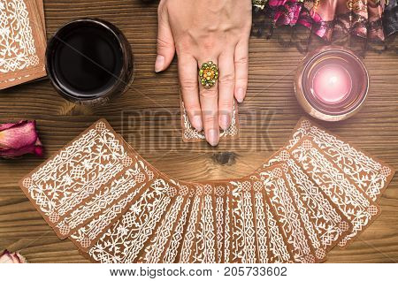 Fortune teller female hands and tarot cards on wooden table. Divination concept.