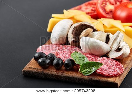 Delicious slices of pizza ingridients on a black table. Closeup