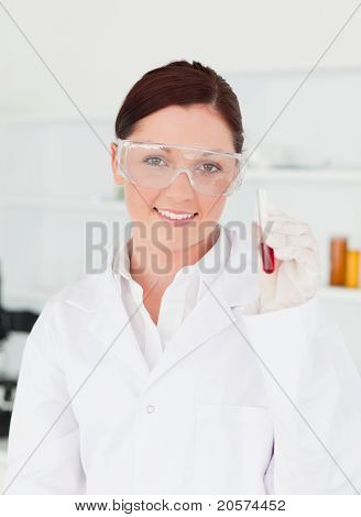 Scienziato sorridente guardando la telecamera mentre si tiene una provetta