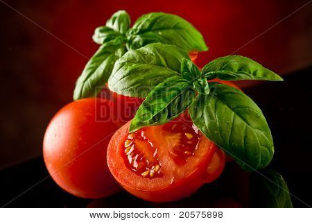 Fette di pomodoro con basilico sul tavolo di vetro