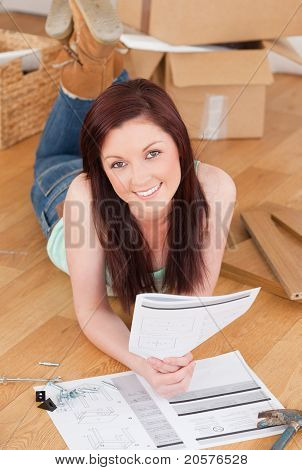 Good Looking ragazza dai capelli rossi in posa mentre la lettura di un manuale prima di fai da te