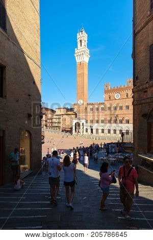 SIENA,ITALY - JULY 23,2017 : Tourists in Siena with a view of Piazza del Campo and the Palazzo Publico