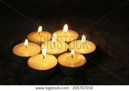 Group Of Small Burning Candles On Dark Background.