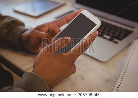Cropped hands of man using phone at counter in cafe