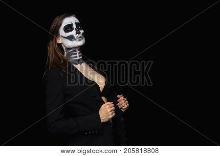 portrait beautiful of brown-haired woman with Halloween skull make up in a stylish black jacket and bra over black background.