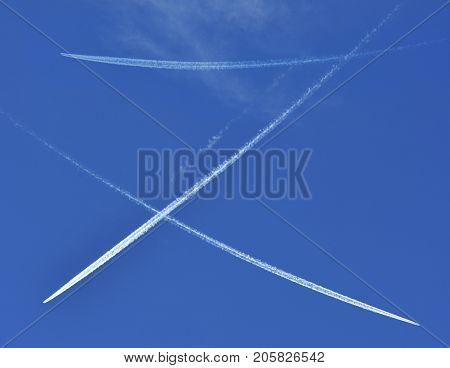 A jet plane flying overhead diagonally with condensation trail.