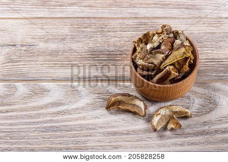 Dried shiitake mushroom in a bow on a wooden table.