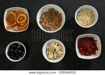 Bowl of dried orange slices, blueberries and breakfast cereals on black background