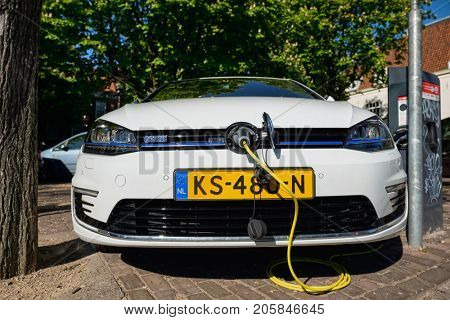 AMSTERDAM, NETHERLANDS - MAY 8, 2017:  Volkswagen Golf GTE petrol-electric hybrid car being charged in the street.