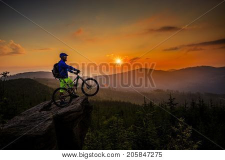 Mountain biker cycling in autumn mountains forest landscape. Man cycling MTB flow trail track. Outdoor sport activity.