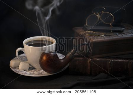 The composition is beautiful from an old book, a cup of coffee, a snuffbox and a pipe to hold a nice evening with an olive box with tobacco