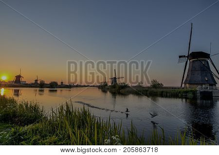 Travelling Concepts and Ideas. UNESCO Heritage Dutch Windmills In Front of The Canal and Sun at Kinderdijk Located in Traditional Village in Holland The Netherlands. Horizontal Image Composition