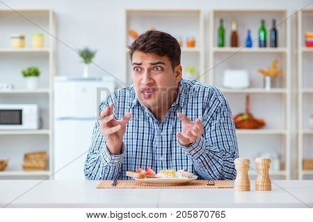 Young husband eating tasteless food at home for lunch