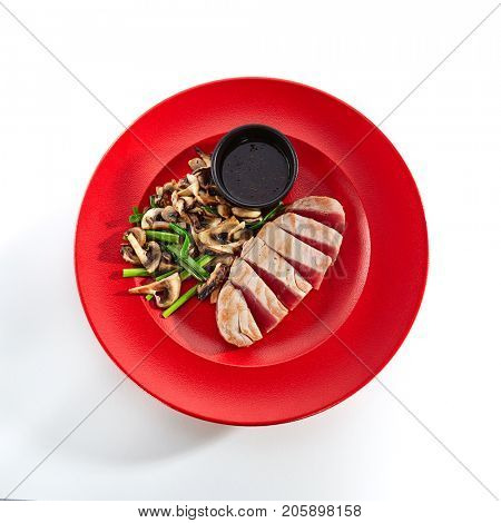 Teppanyaki Japanese and Korean Grill Food - tuna with vegetables mushrooms with sauce on red plate on  white isolated background. Asian menu. Top View
