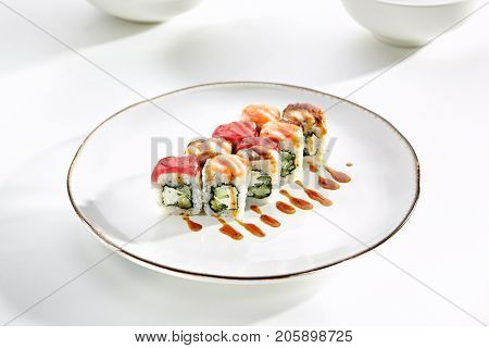 Rainbow sushi rolls with salmon, tuna, eel, Philadelphia cheese and cucumber served on white flat plate. Asian menu for gourmets in luxury restaurant