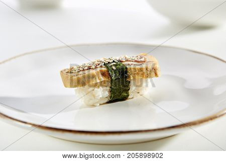 Nigiri sushi with tamagoyaki sweet japanese omelette with sesame on white plate with gold border. Pan Asian restaurant menu