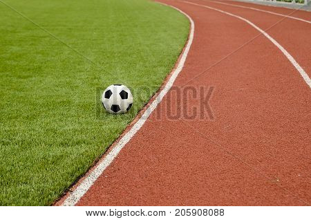 The football is on the artificial grass soccer field in the stadium.
