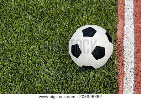 The football is near the line on the artificial grass soccer field in the stadium.