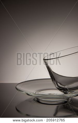 Glass transparent empty mug of tea and saucer on a black and white background