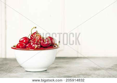 Fresh cherries in bowl on a rustick background