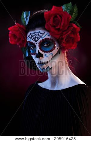 Studio portrait of spooky woman wearing santa muerte mask at halloween, looking at camera.