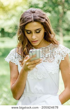 Beautiful young bride chating by mobile phone during wedding.