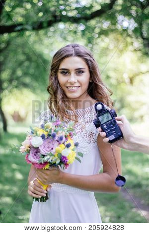 Photographer measuring light with light meter on beautiful girl.