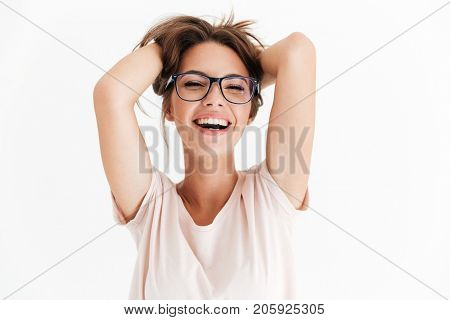 Laughing woman in eyeglasses holding her hair and looking at the camera over white background
