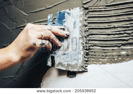 The Worker Applies Glue On A Wall For A Decorative Brick