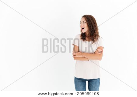 Surprised happy woman with crossed arms looking away over white background