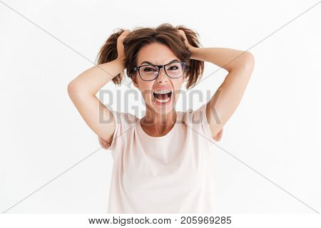 Angry brunette woman in eyeglasses screaming at camera over white background