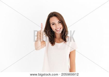 Pleased woman showing thumb up and looking at the camera over white background