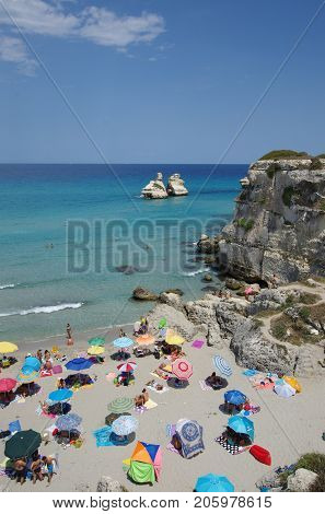 LECCE ITALY - JULY 26 2017: the crowded beautiful beach of Torre dell Orso with the Due Sorelle rocks